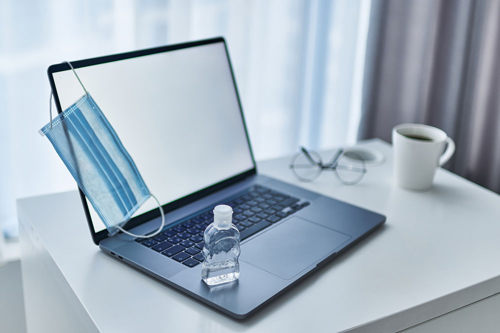 Computer with mask and hand sanitizer during COVID